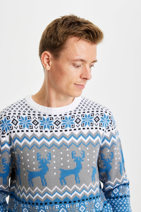 En mand kigger ned og er iført en blå julesweater med mønster på.